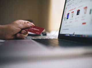 person holding a credit card in front of laptop screen 